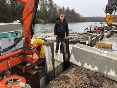Chad Strater stands on a barge at Sea Meadow’s wharf. With the new federal grant, Sea Meadow will replace the wharf’s retaining wall. PHOTO: CLARKE CANFIELD
