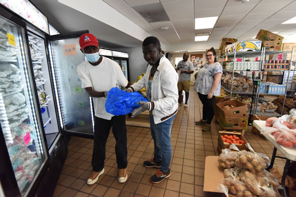 Volunteers at Maine Health’s food pantry at Maine Medical Center in Portland Yannick Lutonda (lef), and Cissako Ekoungola handle the fish.