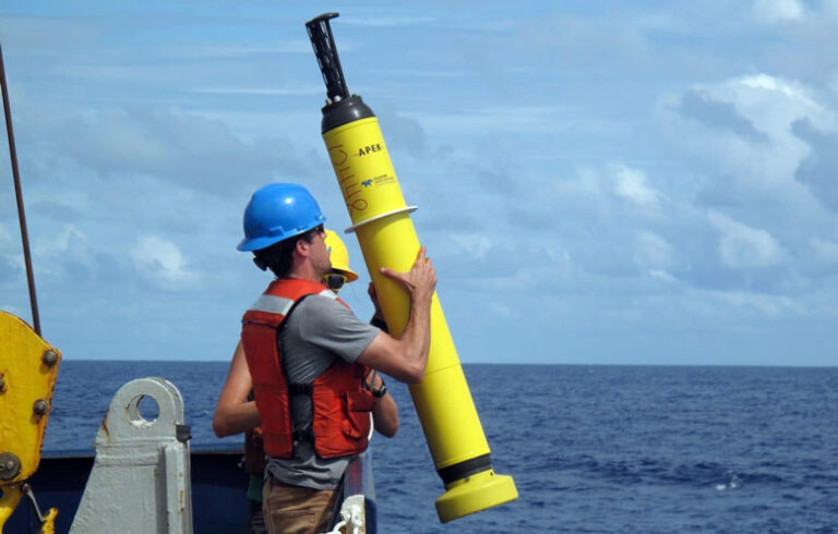 Staff with the Woods Hole Oceanographic Institute prepare to launch a drifter buoy.