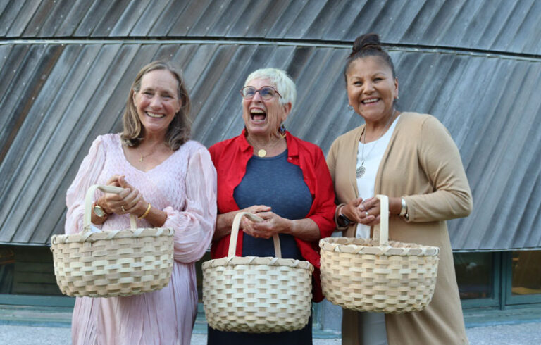 Honorees, from left: Beth Ahearn, Carol Wishcamper, and Rena Newell hold baskets woven by Richard Silliboy, vice chief of the Mi’kmaq Nation during Nihkaniyane on July 11. PHOTO: EMMA DAVIS/MAINE MORNING STAR