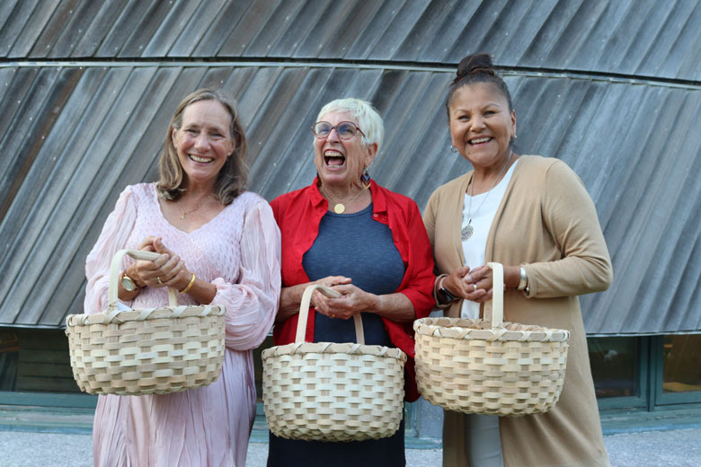 Honorees, from left: Beth Ahearn, Carol Wishcamper, and Rena Newell hold baskets woven by Richard Silliboy, vice chief of the Mi’kmaq Nation during Nihkaniyane on July 11. PHOTO: EMMA DAVIS/MAINE MORNING STAR