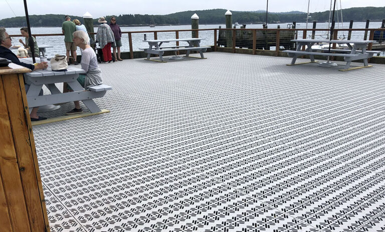 Visitors enjoy sitting on the town dock in Castine’s harbor area. The dock was destroyed by the January storms, but the new decking material will allows waters from storm surge to rise through while encountering less resistance. PHOTO: TOM GROENING