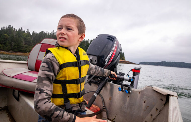 Luke Maker, 8, of Machiasport runs the family skiff through a cove earlier this summer using an electric outboard purchased through a grant from Island Institute, publisher of The Working Waterfront. Luke and is father, Ryan, fish for lobster. PHOTO: JACK SULLIVAN