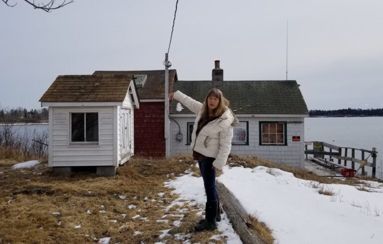 woman pointing at small white building