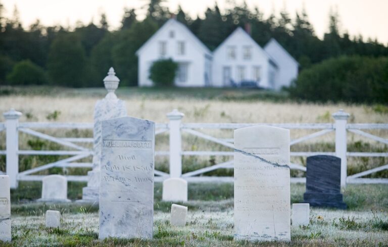 old marble headstones, white house in distance