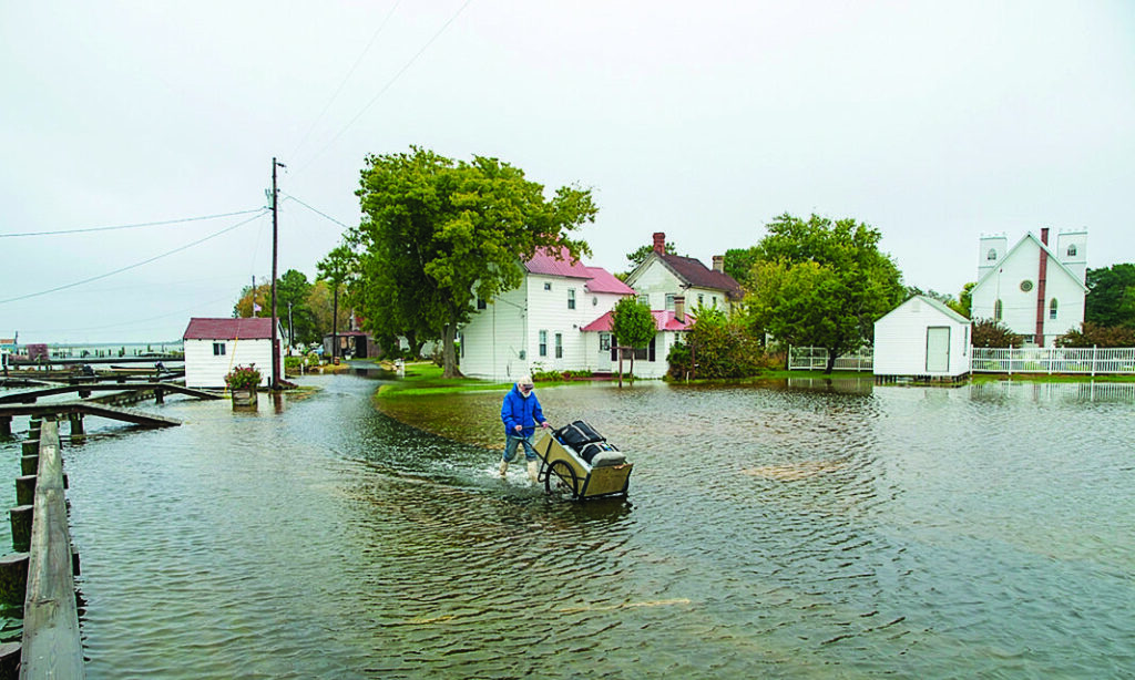 man pushing luggage through ankle-deep water