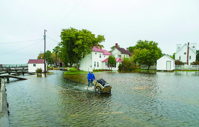 man pushing luggage through ankle-deep water