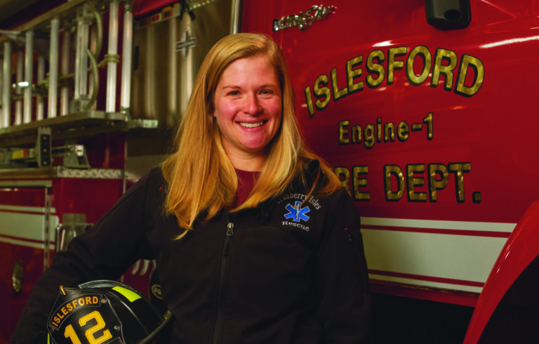 female firefighter posed in front of fire truck