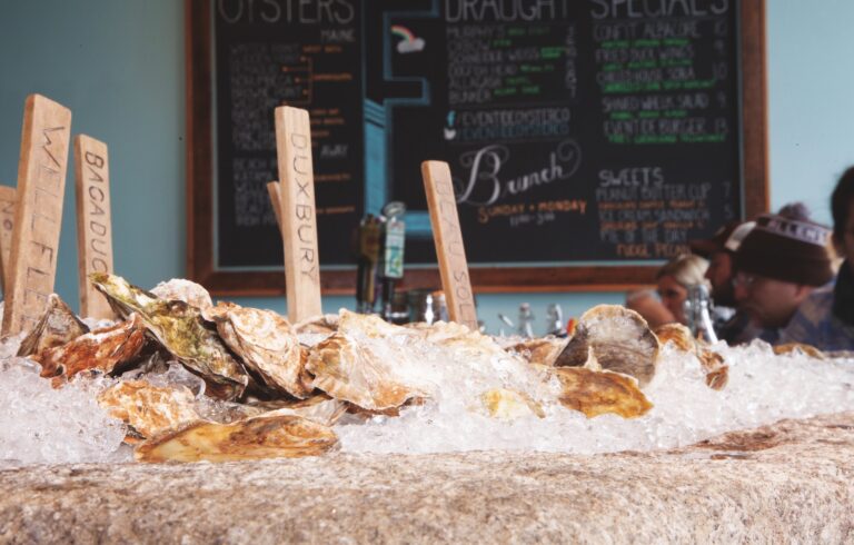 oysters on a bed of ice with a menu board in background