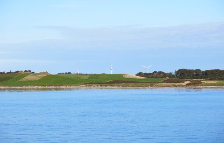 windmills in the distance behind a body of water