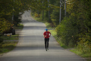 man in red shirt running on paved road