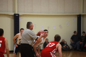 basketball referee about to throw up the ball to begin game