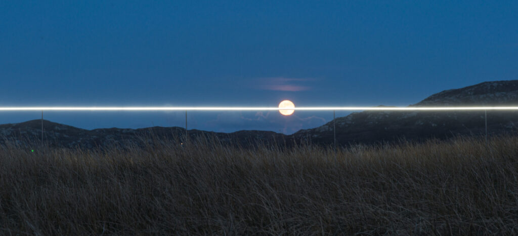 landscape art installation, line of light along horizon, striking through full moon