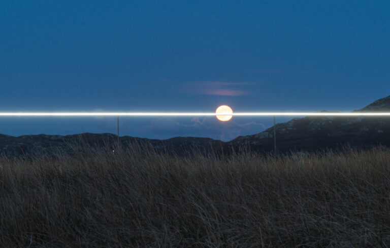 landscape art installation, line of light along horizon, striking through full moon