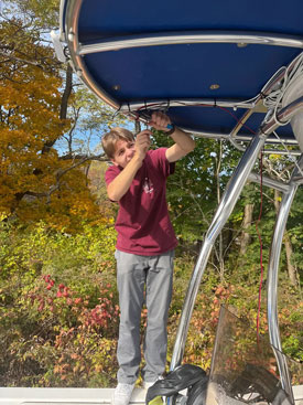 A student helps to install a solar panel on the Sea Lion in October. PHOTO: COURTESY BELFAST MARINE INSTITUTE